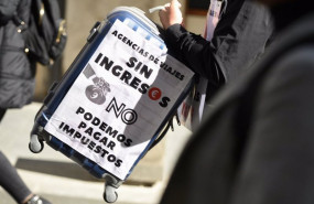 ep archivo   una mujer con una maleta y una pancarta participa en la concentracion de asociaciones