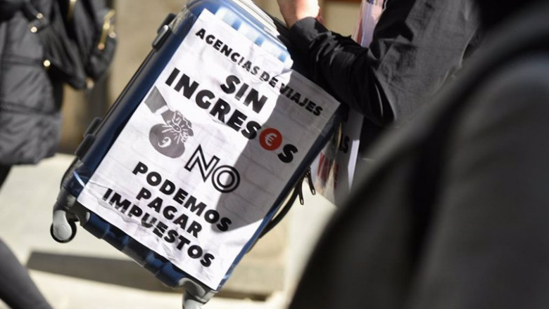 Archivo - Una mujer con una maleta y una pancarta participa en la concentración de asociaciones representativas de las agencias de viajes valencianas. | Jorge Gil - Europa Press - Archivo ep archivo una mujer con una maleta y una pancarta participa en la concentracion de asociaciones