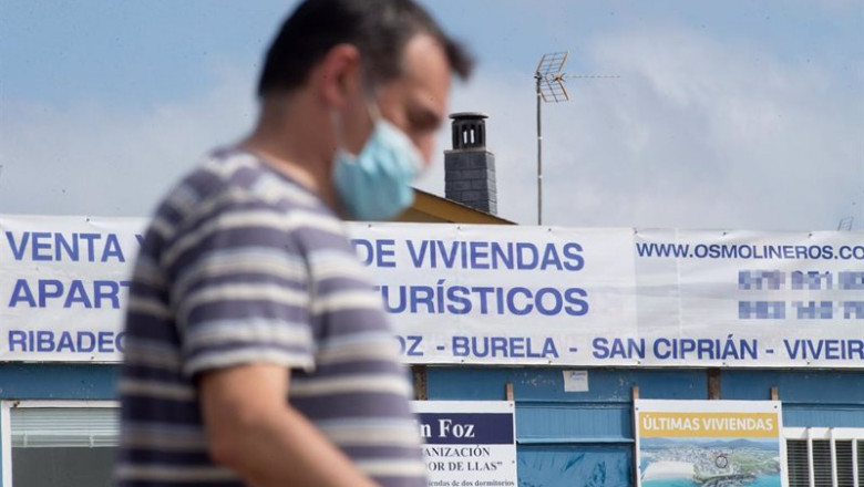 Un hombre camina junto a un cartel de viviendas en venta en A Mariña (Lugo/Galicia) a 26 de julio de 2020. La comarca mantiene este domingo 51 casos activos de COVID-19 tras una nueva alta y un nuevo contagio con respecto al sábado. | Carlos Castro - Europa Press - Archivo ep galicia a 26 de julio de 2020 la comarca mantiene este domingo 51 casos activos de covid-19 tras