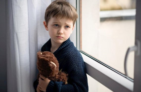 ep nino esta abrazando a su osito de peluche de pie junto a la ventana dia lluvioso concepto de