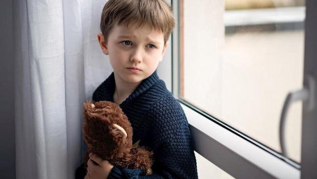 ep nino esta abrazando a su osito de peluche de pie junto a la ventana dia lluvioso concepto de