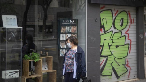 ep una mujer protegida con mascarilla y guantes camina con el carro de la compra delante de una
