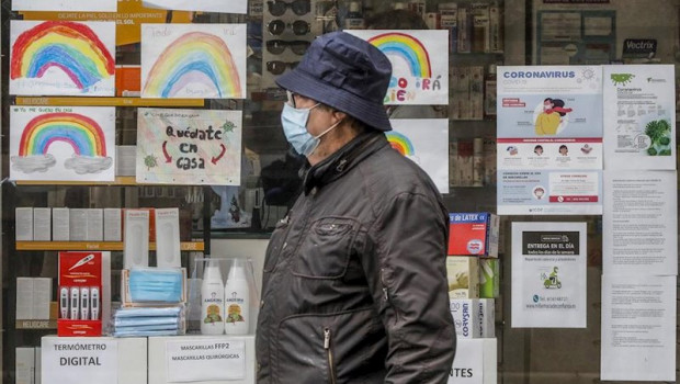ep un hombre con mascarilla pasa junto a una farmacia con dibujos infantiles en su escaparate