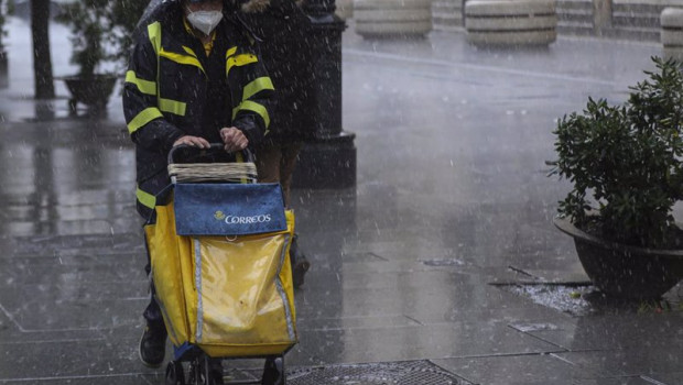ep archivo   un repartidor de correos trabaja bajo la lluvia protegido con un impermeable