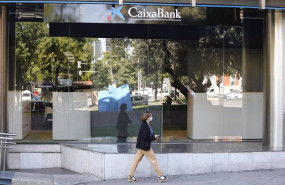 ep archivo   una mujer pasa por al lado de las oficinas de caixabank en el paseo castellana en