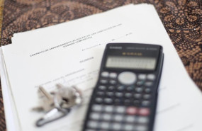 ep una calculadora y unas llaves sobre un contrato de alquiler de una habitacion en una vivienda