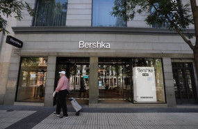 ep un anciano con mascarilla y carro pasa delante de una tienda de bershka propiedad de inditex
