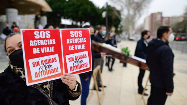 ep archivo - una mujer sostiene una pancarta donde se lee sos agencias de viaje