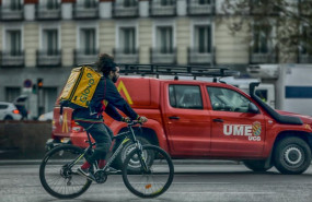 ep un repartidor en bici circula por una calle de madrid al lado de un vehiculo de la ume el 15 de