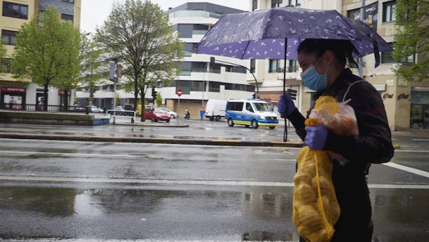 ep una mujer se protege de la lluvia con un paraguas mientras camina con una bolsa de patatas