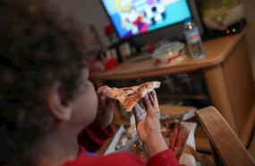 ep un nino beneficiario de beca comedor en la comunidad de madrid come un trozo de pizza mientras ve