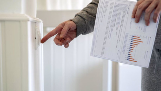 ep archivo   un hombre enciende un interruptor con una factura de luz en la mano