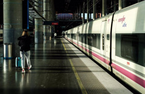 ep una mujer camina por el anden junto a un tren de ave de renfe estacionado en las vias de la