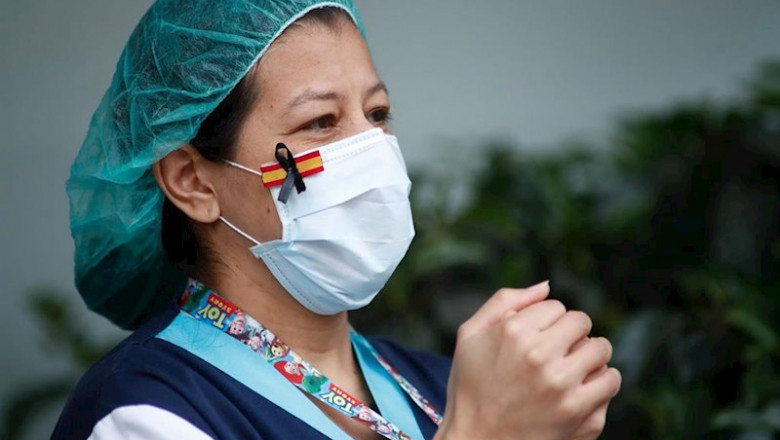 ep una sanitaria con una mascarilla que muestra una bandera de espana con un lazo negro de luto por ep una sanitaria con una mascarilla que muestra una bandera de espana con un lazo negro de luto por