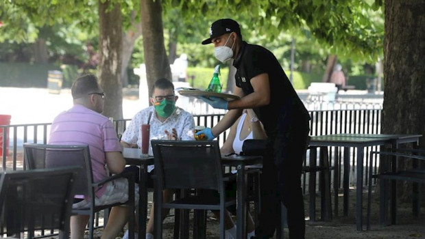 ep un camarero protegido con mascarilla atiende a una mesa de una terraza