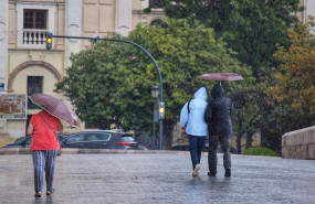 ep varias personas pasean por una calle de valencia con paraguas y chubasqueros durante el temporal