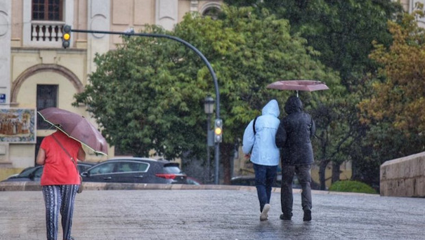 ep varias personas pasean por una calle de valencia con paraguas y chubasqueros durante el temporal
