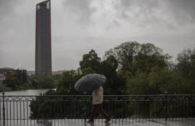 ep un hombre protegido con un paraguas camina por el puente de triana durante la alerta amarilla por