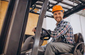 man working warehouse driving forklift 