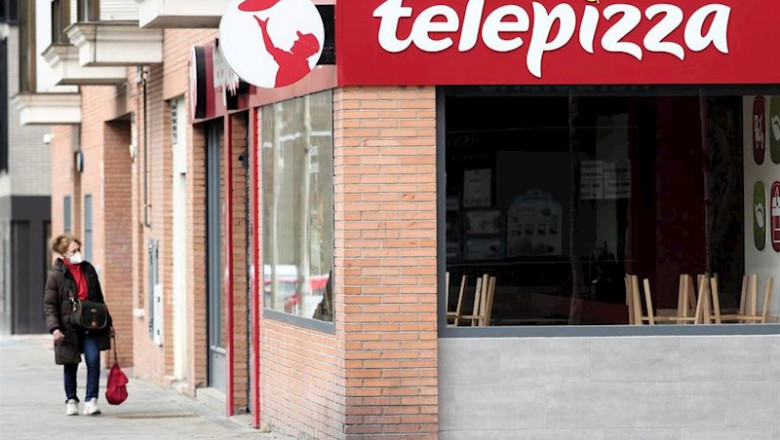 Una mujer protegida con mascarilla pasea cerca de un local de Telepizza el mismo día en el que han comenzado a servir menús para alumnos madrileños con beca comedor y así evitar que les falten alimentos por la crisis del coronavirus, en Madrid. | Eduardo Parra - Europa Press ep una mujer protegida con mascarilla pasea cerca de un local de telepizza el mismo dia en el que
