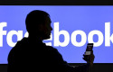ep un hombre con un telefono movil delante de un cartel de facebook