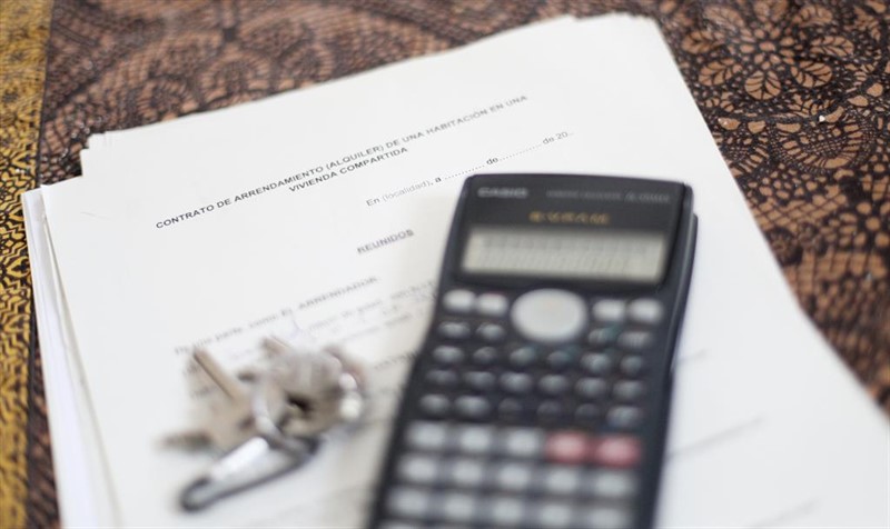 ep una calculadora y unas llaves sobre un contrato de arrendamiento alquiler