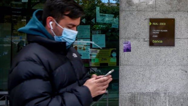 ep un joven mira su movil delante de una sucursal de bankia en collado villalba madrid espana